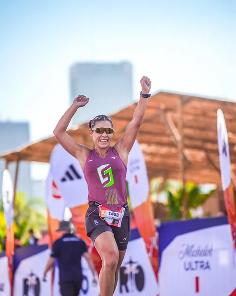 Atleta de braços erguidos comemorando na chegada de uma prova de trail run.