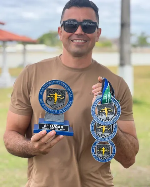 Atleta sorrindo com troféu de 5º lugar e medalhas.