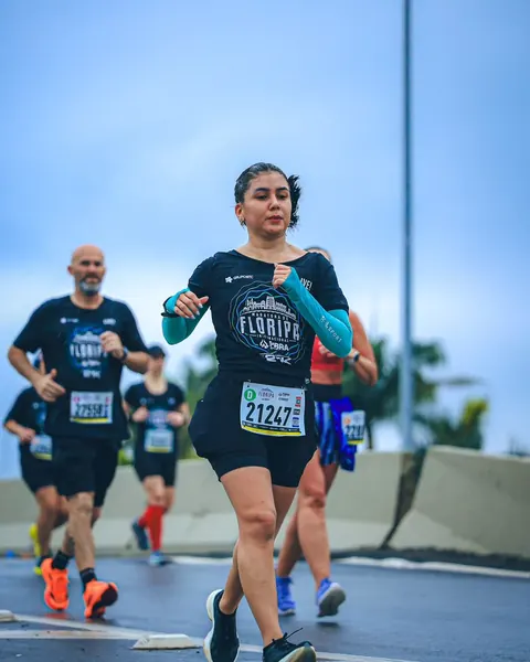 Atleta correndo em prova de rua ao lado de outros corredores.