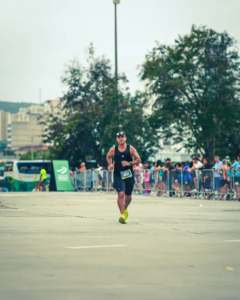 Atleta correndo em prova com público ao fundo.