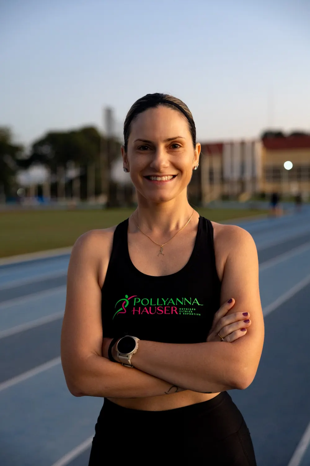 Pollyanna Hauser numa pista de atletismo, de braços cruzados, com o uniforme da sua marca.